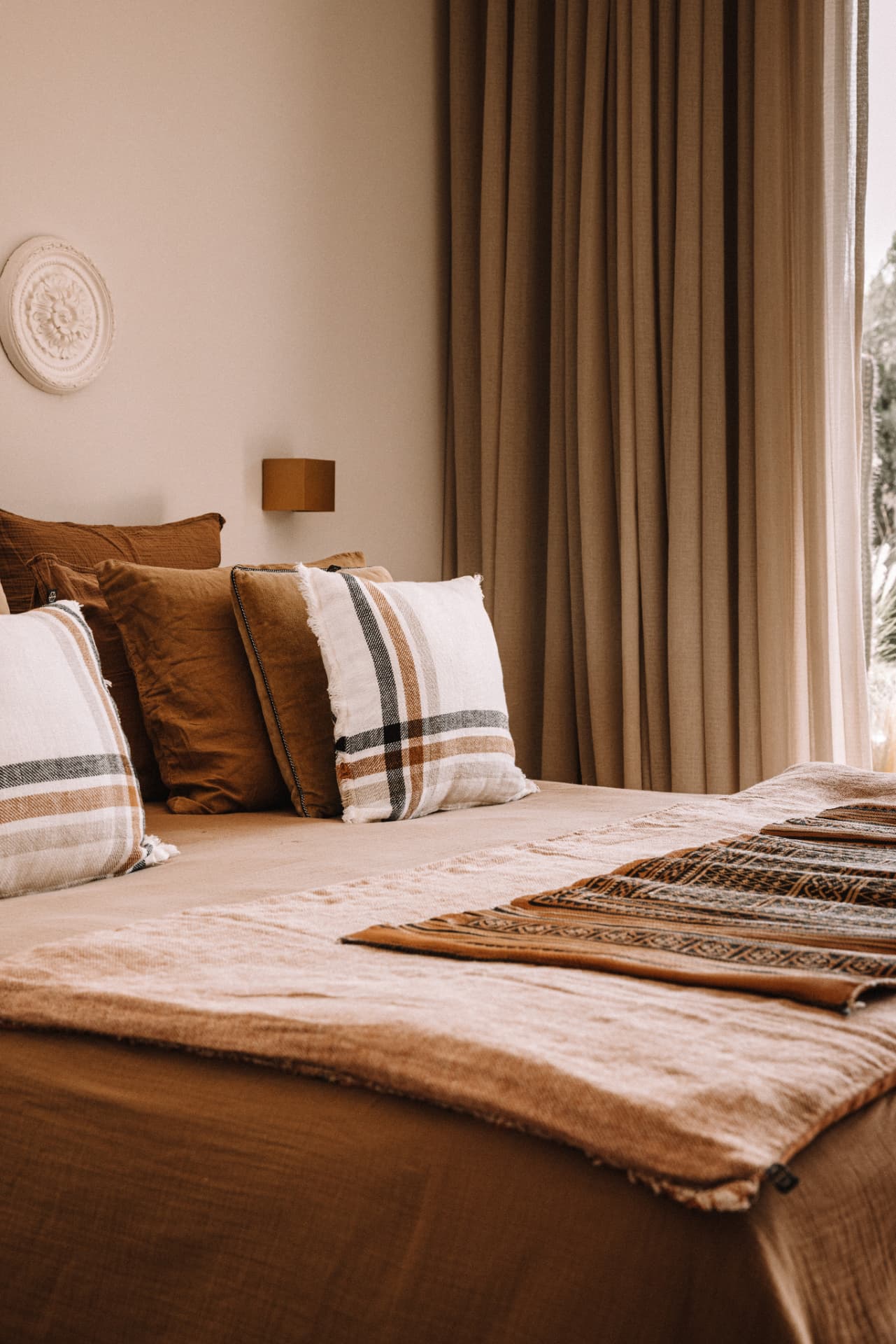 Bedroom in terracotta and chocolate tones with Berber textiles and linen curtains
