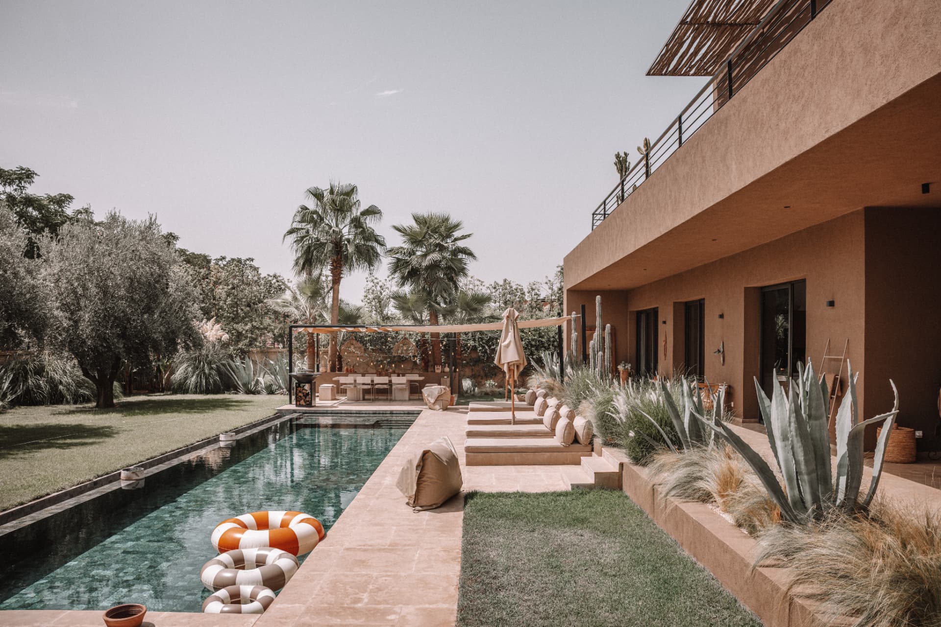 Garden and pool of Sophie and Grégo's home, an earth-toned villa surrounded by palms and olive trees